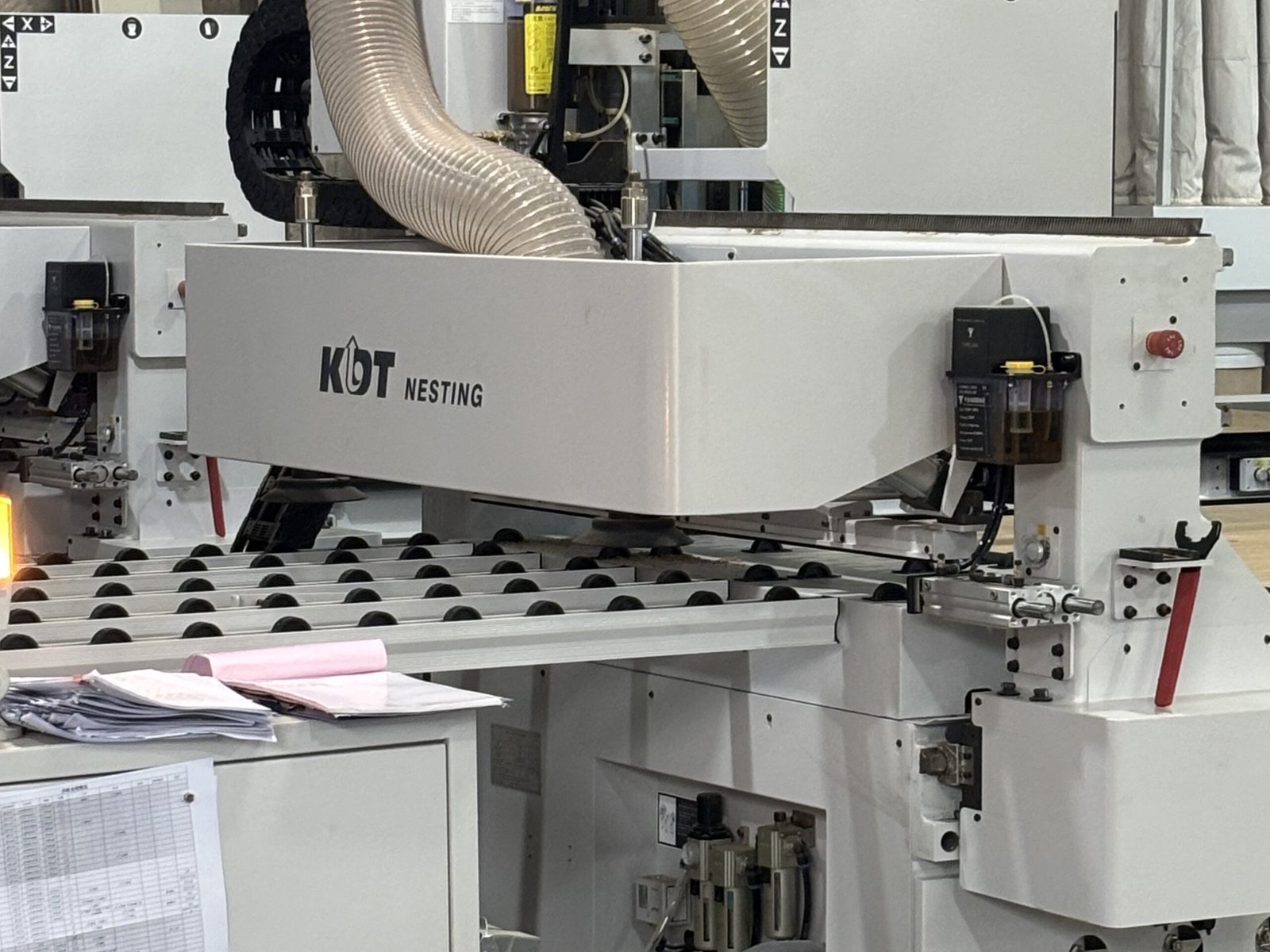 Automated CNC nesting router cutting custom cabinet panels in a cabinet manufacturing facility.